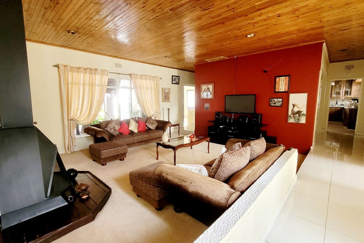Spacious living room featuring a wood-paneled ceiling, a prominent freestanding fireplace, and a mix of tiled and carpeted flooring.