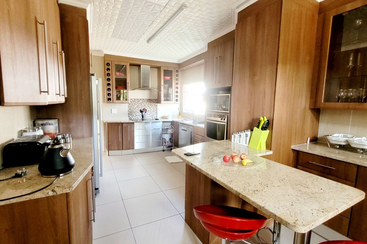 A functional kitchen featuring wood-finish cabinetry, granite countertops, a breakfast bar, and integrated appliances, offering a practical layout for daily cooking and dining.