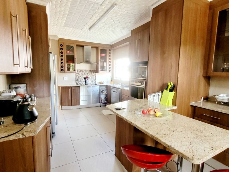 A functional kitchen featuring wood-finish cabinetry, granite countertops, a breakfast bar, and integrated appliances, offering a practical layout for daily cooking and dining.