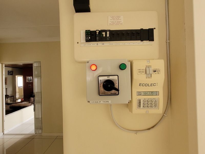 A wall-mounted electrical distribution board featuring a prepaid electricity meter and a generator changeover switch located in the hallway.