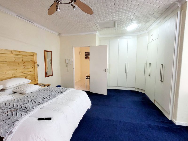 Spacious bedroom featuring extensive built-in cabinetry, blue carpeting, and a textured ceiling with an integrated fan.