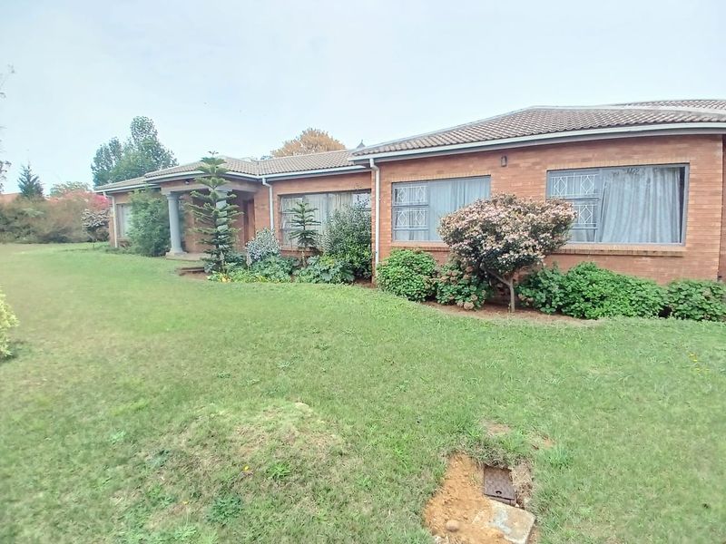 A single-story brick house featuring a tiled roof, security-barred windows, and a well-established front garden with a covered entrance area.