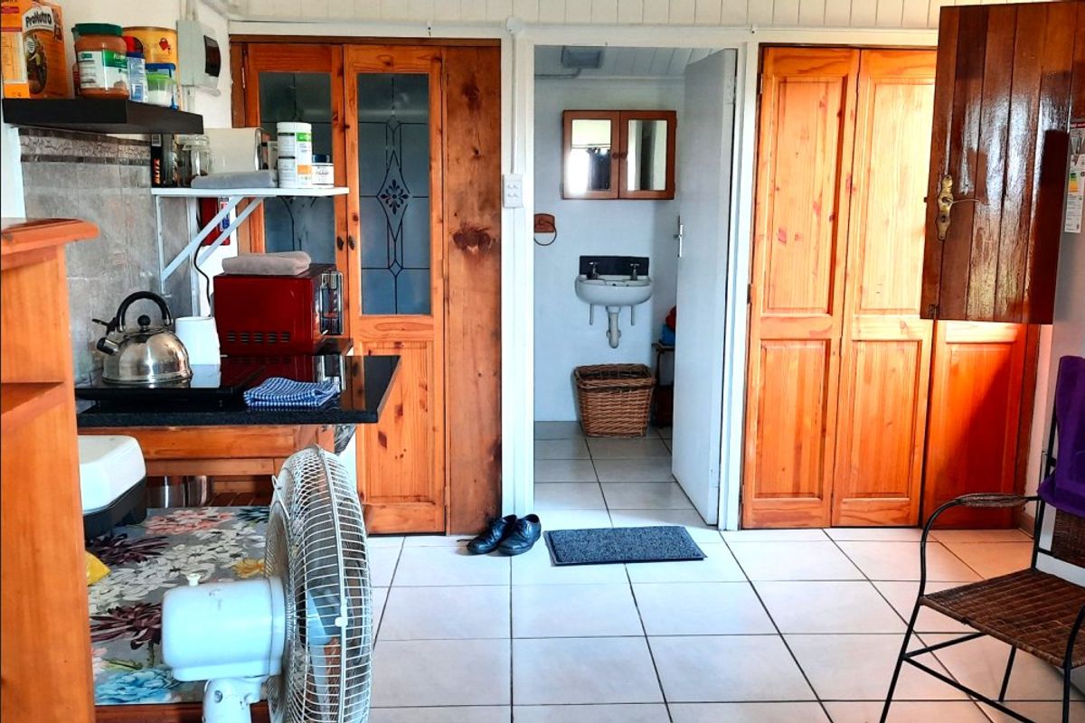 Open plan area featuring tiled flooring, wooden cabinetry, and a small adjacent bathroom with a wall-mounted sink.