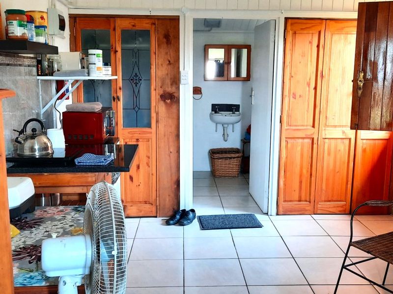 Open plan area featuring tiled flooring, wooden cabinetry, and a small adjacent bathroom with a wall-mounted sink.