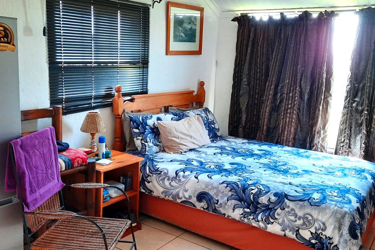 A functional bedroom featuring tiled flooring, venetian blinds, and curtain tracks, providing a comfortable and practical living space.