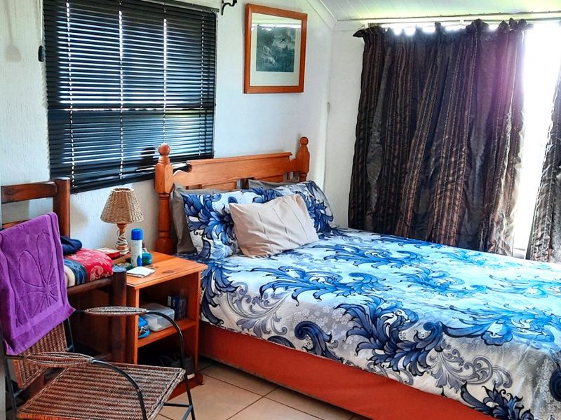 A functional bedroom featuring tiled flooring, venetian blinds, and curtain tracks, providing a comfortable and practical living space.