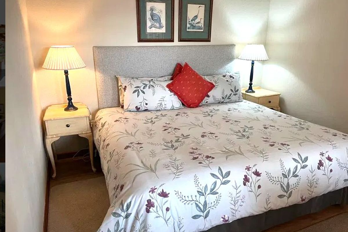 A cozy bedroom featuring a neutral upholstered headboard and warm ambient lighting, providing a comfortable and inviting sleeping space.