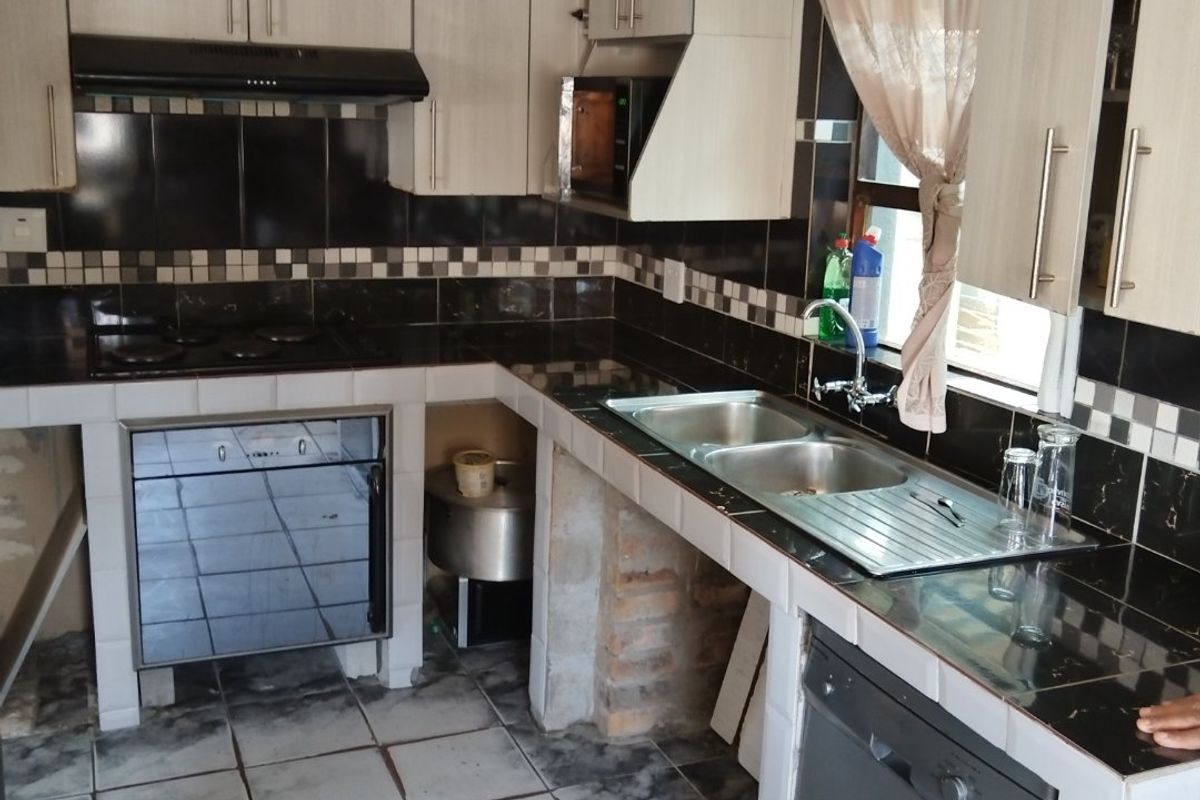 A functional kitchen featuring tiled countertops, built-in cabinetry, and integrated appliances, offering a solid foundation for a modern renovation or cosmetic update.