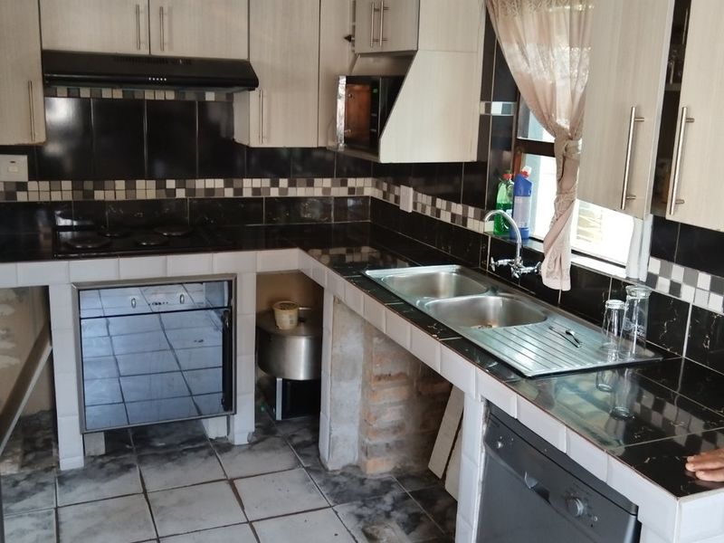 A functional kitchen featuring tiled countertops, built-in cabinetry, and integrated appliances, offering a solid foundation for a modern renovation or cosmetic update.