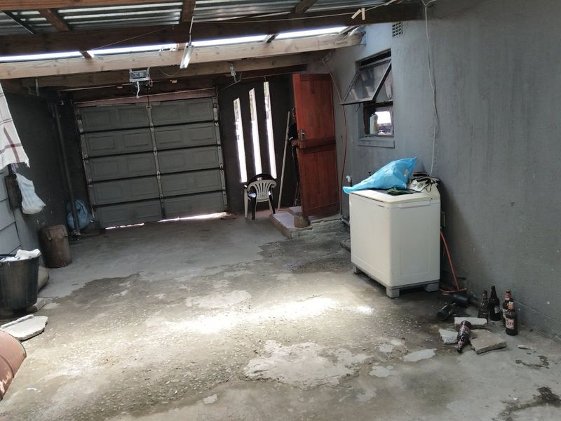 A functional garage space featuring a sectional door, exposed timber roof beams, and concrete flooring, offering potential for storage or workshop use.