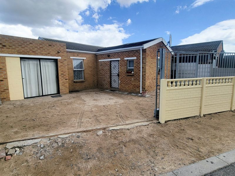 Front exterior view of a face brick house featuring a sliding door, security gate, and a precast boundary wall with a metal driveway gate.
