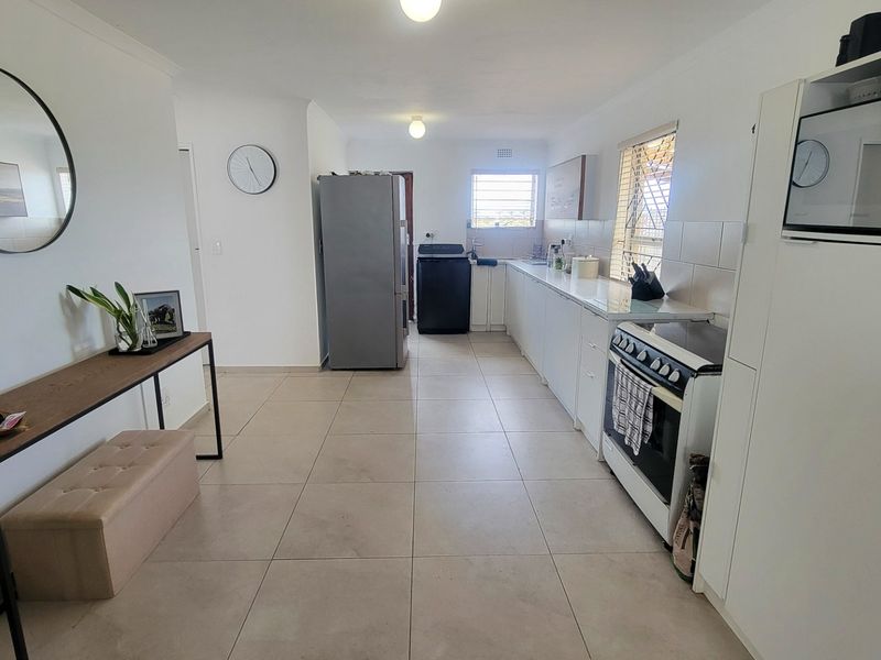 A functional kitchen featuring tiled flooring, ample built-in cabinetry, a tiled backsplash, and a freestanding stove with an integrated microwave unit.