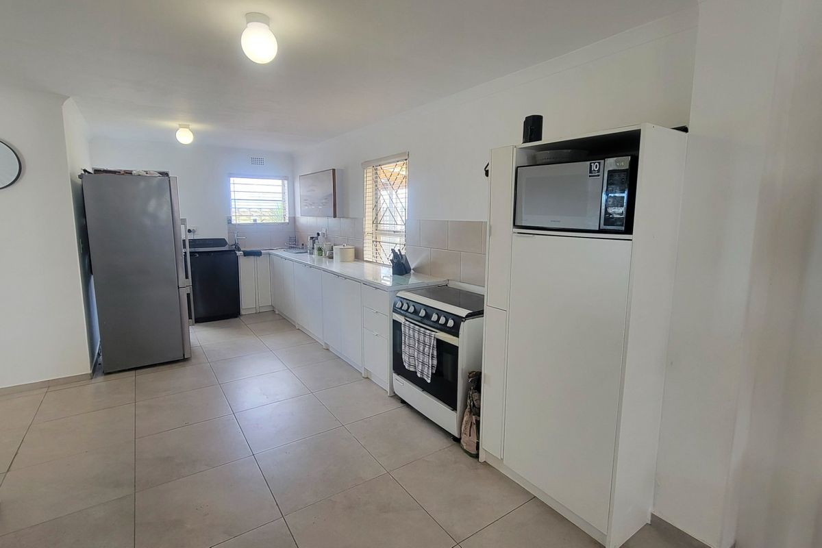 A functional kitchen featuring white cabinetry, tiled flooring, a tiled backsplash, and a freestanding stove with integrated microwave housing.