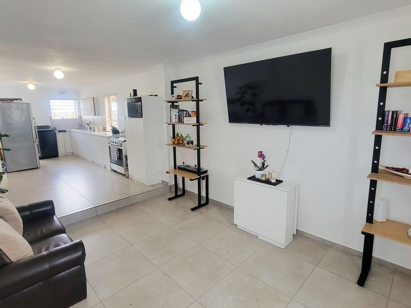 Open-plan living and kitchen area featuring tiled flooring, modern cabinetry, and a split-level layout connecting the lounge to the kitchen space.