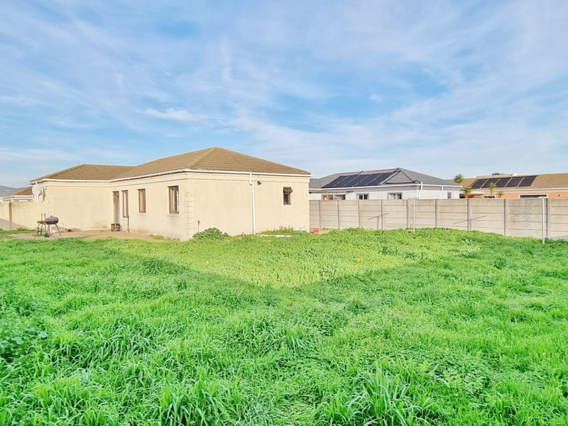 Spacious rear garden area featuring a large lawn, enclosed by precast concrete boundary walls, with a view of the rear building elevation.