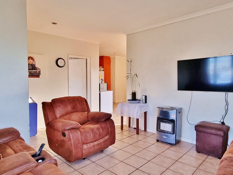 A functional living room featuring tiled flooring and recessed downlighting, providing a neutral base for potential interior updates.
