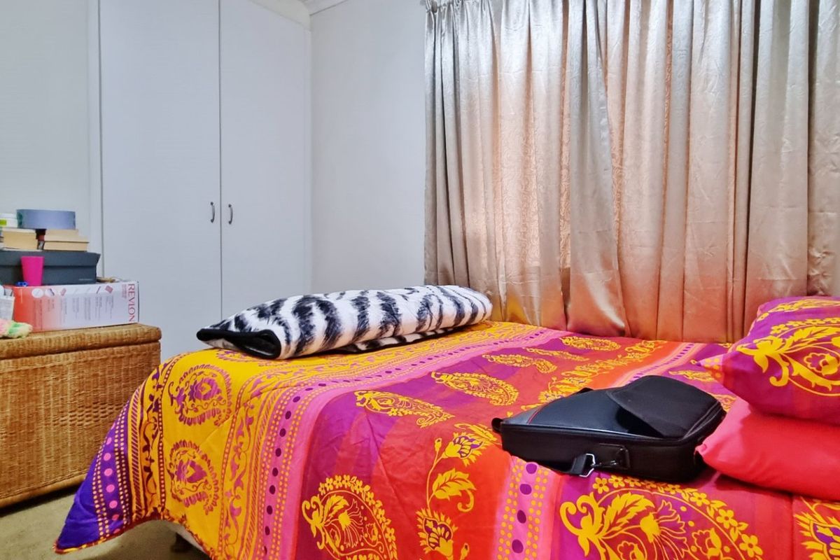 A functional bedroom featuring a built-in wardrobe and window with curtains, providing a comfortable and practical living space.