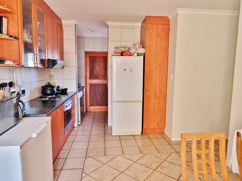 A functional kitchen featuring wooden cabinetry, tiled flooring, and a tiled backsplash, providing a practical layout for daily meal preparation.