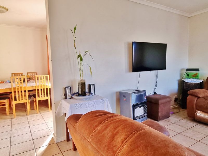 An open-plan living and dining area featuring neutral wall finishes and tiled flooring throughout.