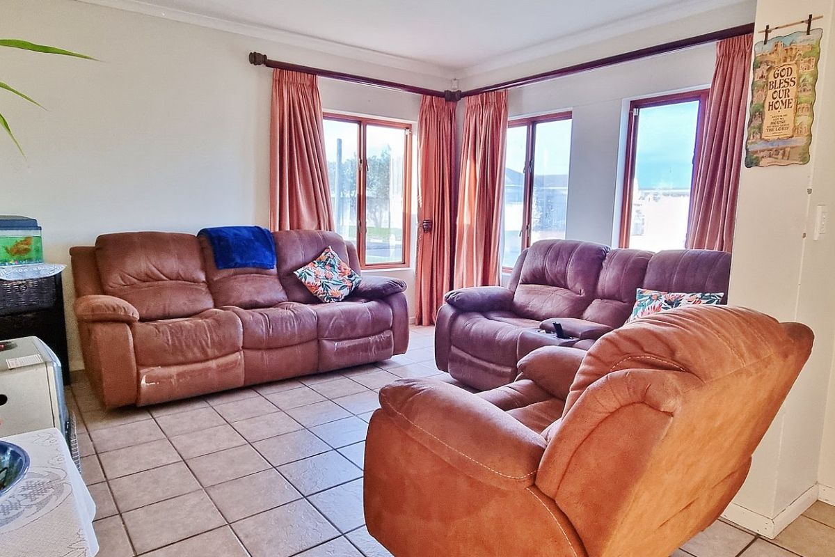 A living room featuring tiled flooring and large windows with timber frames, providing natural light to the space.