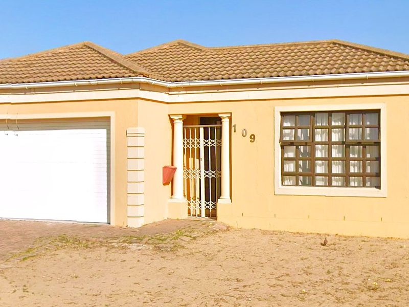 Front elevation of a single-story house featuring a double garage, security gate, and tiled roof, set on a property with an unlandscaped front yard.
