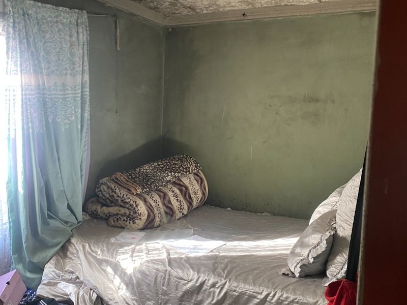 A bedroom featuring textured ceiling tiles and painted walls, requiring cosmetic updates and maintenance to improve the overall condition of the space.