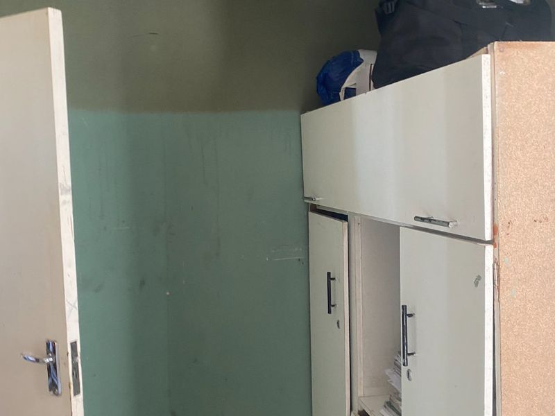 A bedroom featuring a built-in cupboard and a decorative pressed metal ceiling, currently showing signs of wear and requiring maintenance.
