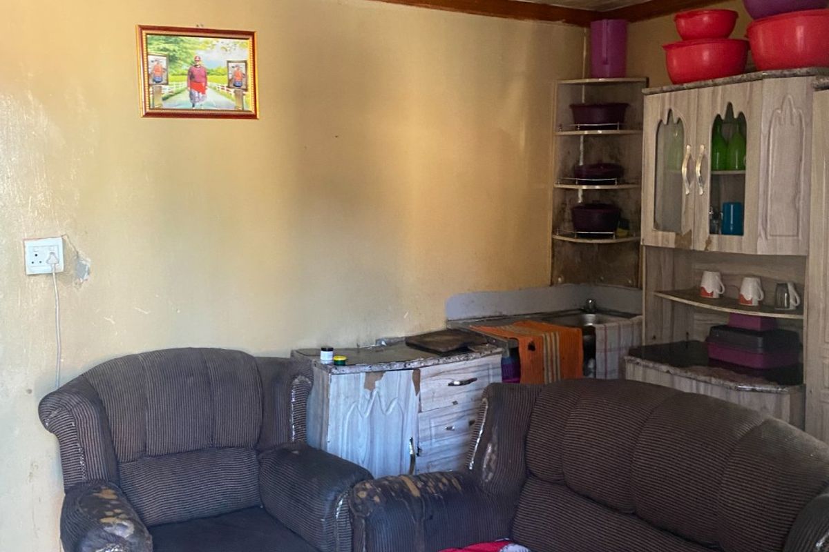 A compact kitchen area featuring built-in cabinetry, tiled flooring, and textured ceiling tiles, currently showing significant signs of wear and dated finishes.