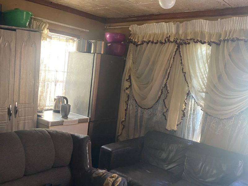 A living area featuring tiled flooring and textured ceiling tiles, requiring cosmetic updates to improve the overall condition and aesthetic appeal.