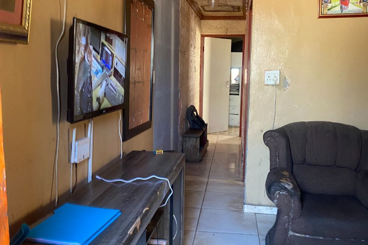 A living area featuring tiled flooring and textured ceiling tiles, showing signs of wear and requiring cosmetic updates to improve the overall aesthetic.