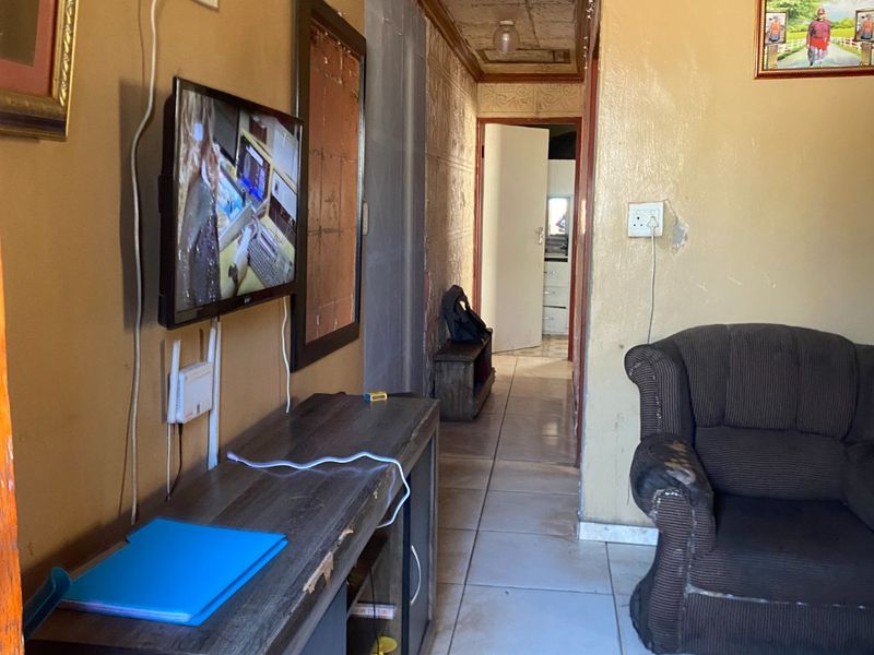 A living area featuring tiled flooring and textured ceiling tiles, showing signs of wear and requiring cosmetic updates to improve the overall aesthetic.