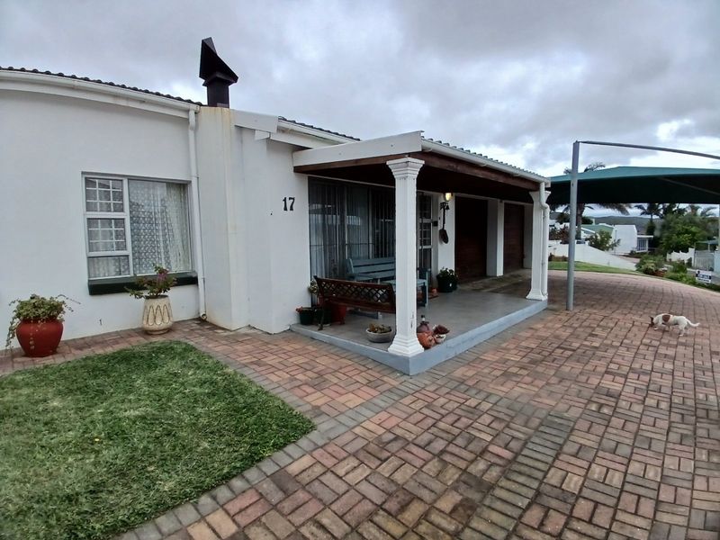 Front elevation of the house featuring a paved driveway, covered patio area with decorative columns, and a chimney stack.