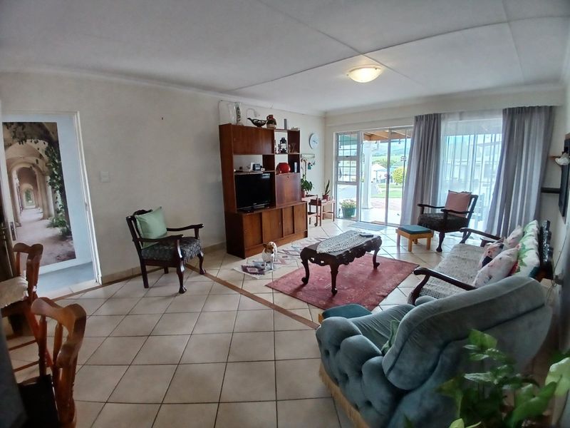Spacious living room featuring neutral tiled flooring and large sliding glass doors that provide natural light and access to the outdoor patio area.