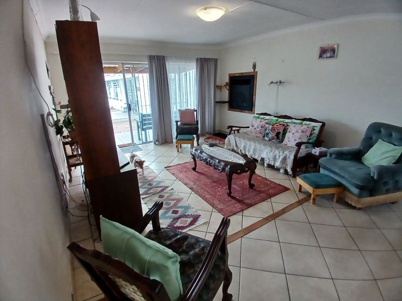 A spacious living room featuring tiled flooring and a sliding glass door that provides access to the outdoor patio area.
