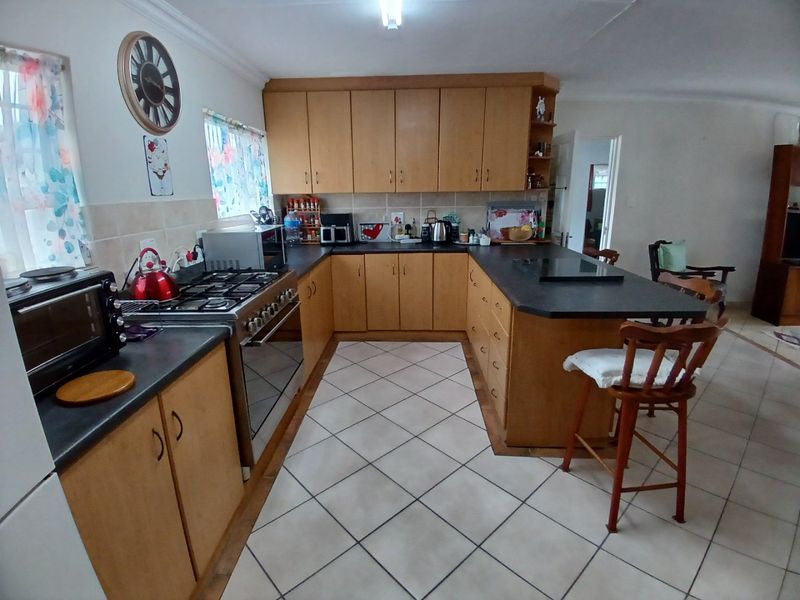 A functional kitchen featuring wooden cabinetry, a gas stove with oven, tiled flooring, and a breakfast bar counter.