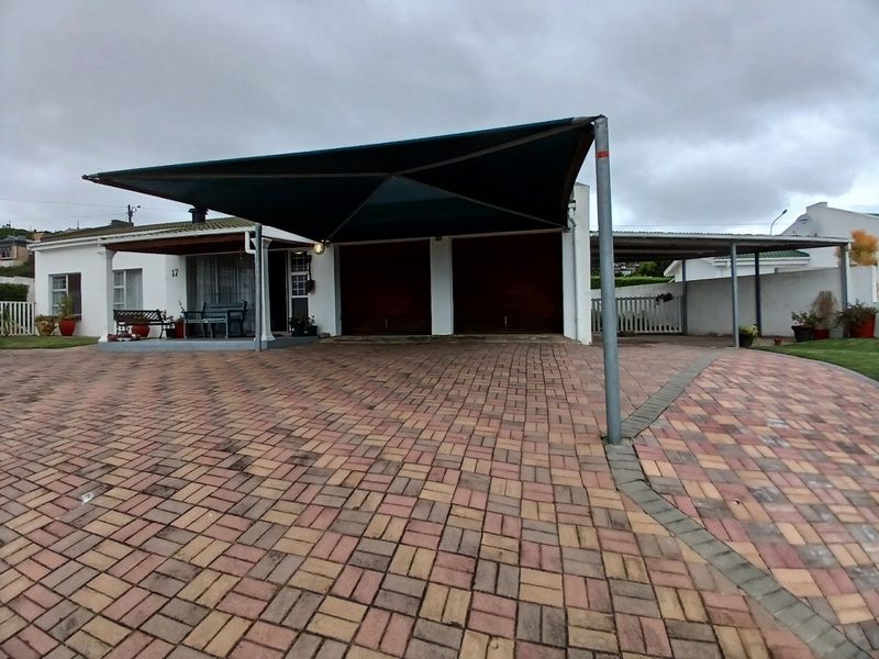 Front exterior view featuring a paved driveway, double garage with shade sail cover, and a covered patio entrance.