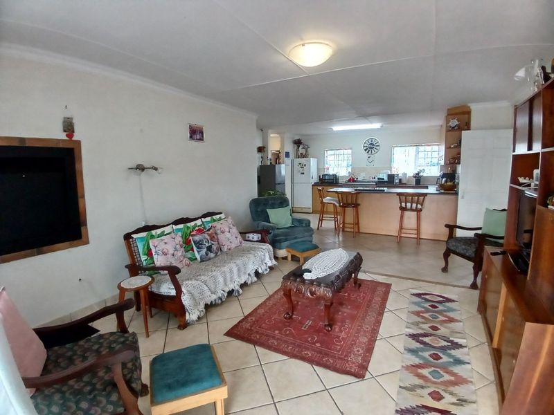 Spacious open-plan living area featuring tiled flooring and a functional kitchen with a breakfast bar island, offering a versatile layout for family living.