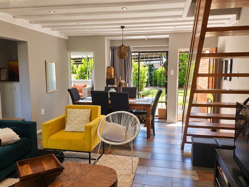 Open plan living and dining area featuring a wooden staircase, tiled flooring, and direct access to the rear garden through sliding glass doors.