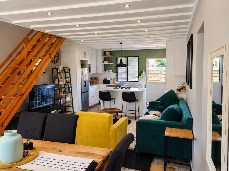 Spacious open-plan living area featuring a modern kitchen with island, exposed beam ceilings, and a wooden staircase leading to the upper level.