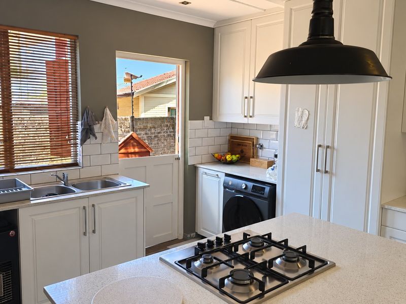 Modern kitchen featuring white cabinetry, stone countertops, a gas hob, subway tile backsplash, and direct access to the exterior.