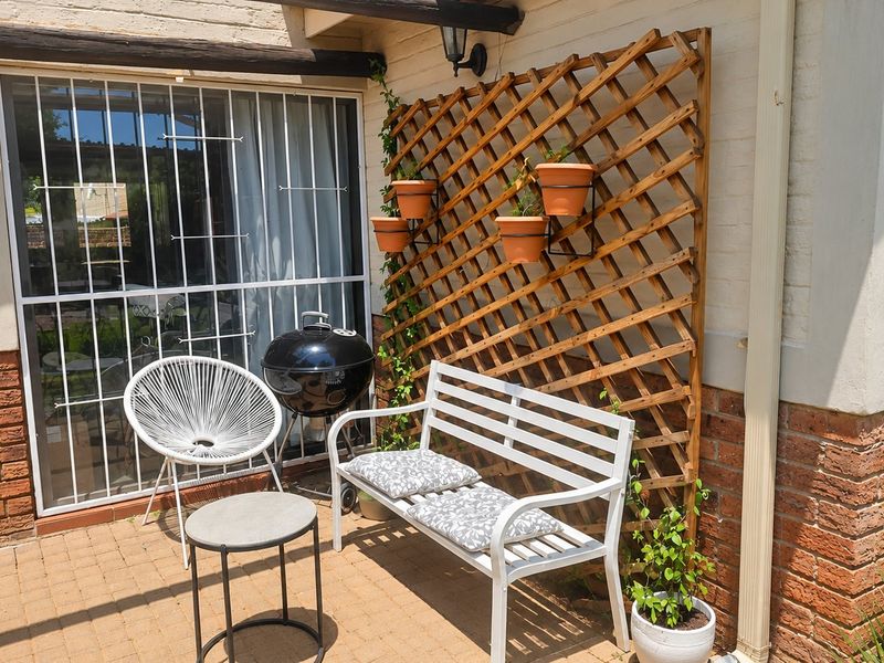 A paved outdoor patio area featuring a brick facade, security gate, and wall-mounted lighting, providing a functional space for outdoor relaxation.