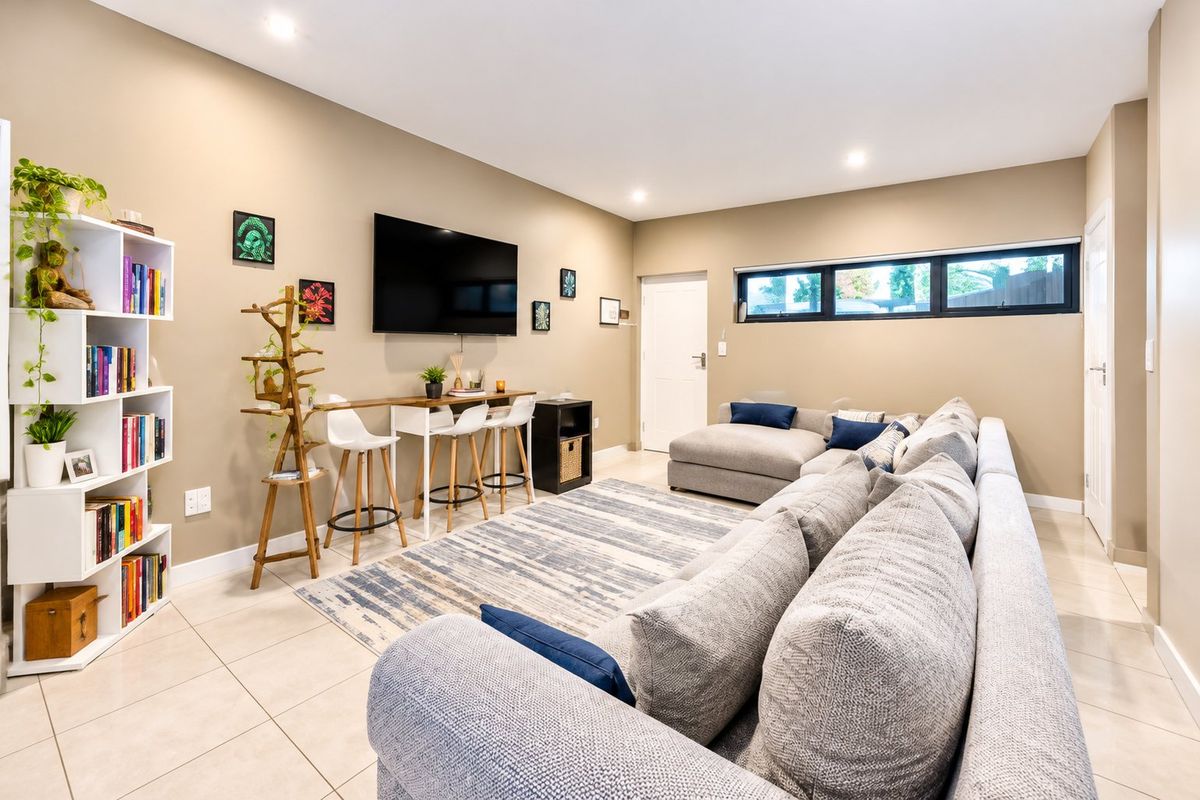 A well-maintained living room featuring neutral tiled flooring, recessed downlighting, and a horizontal clerestory window providing natural light.
