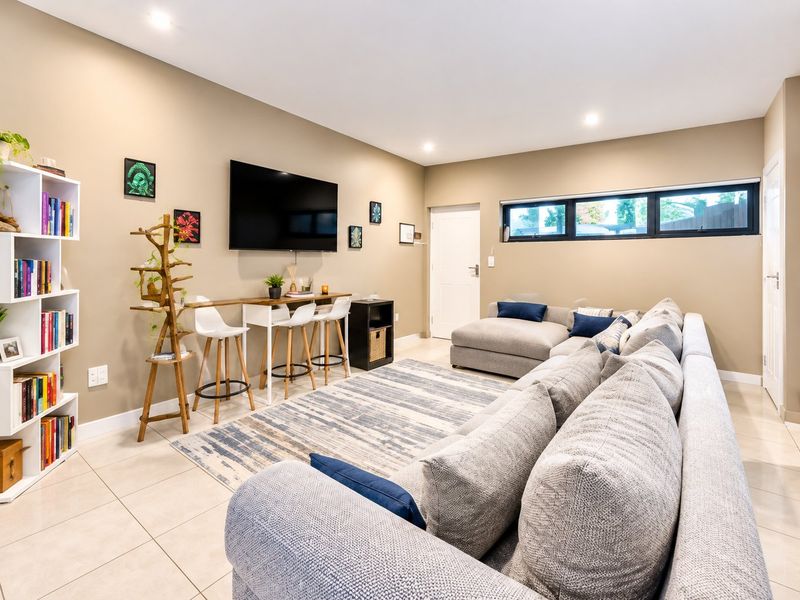 A well-maintained living room featuring neutral tiled flooring, recessed downlighting, and a horizontal clerestory window providing natural light.