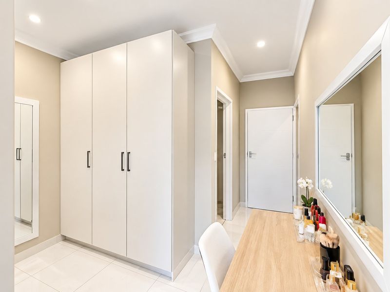 A well-maintained bedroom featuring modern built-in cupboards, recessed downlighting, and neutral tiled flooring, creating a clean and functional living space.