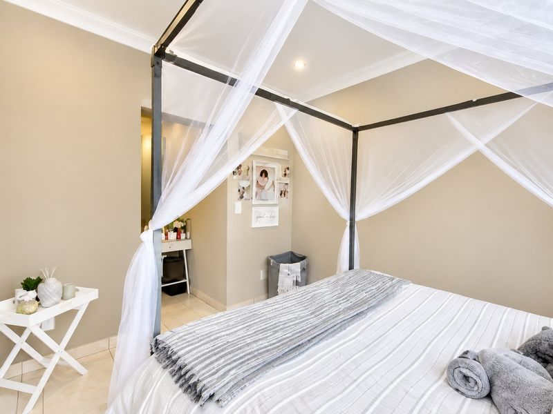 A well-maintained bedroom featuring neutral wall tones, tiled flooring, and recessed downlighting, offering a clean and comfortable living space.