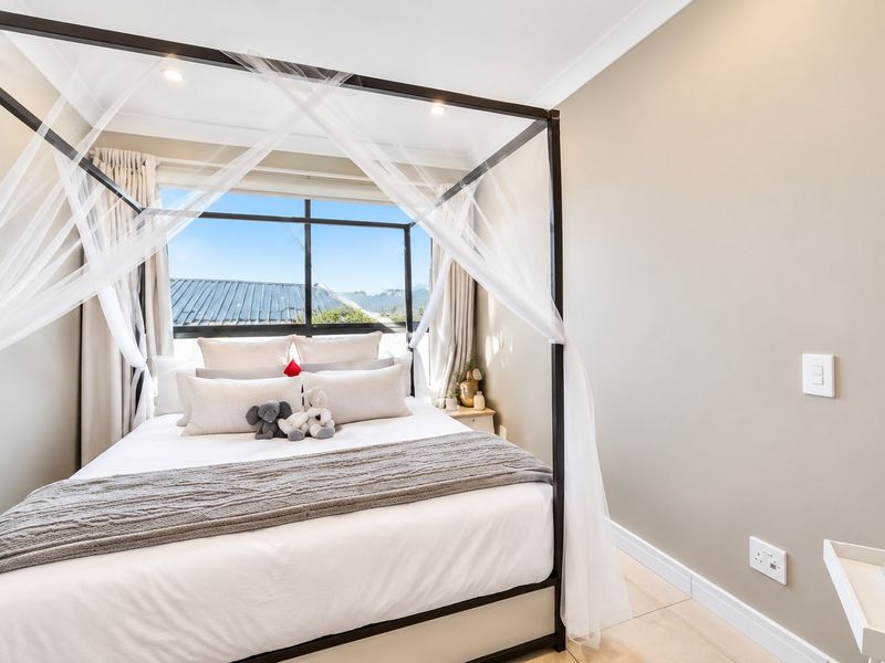 A bright and well-maintained bedroom featuring tiled flooring, recessed downlighting, and large windows with views.