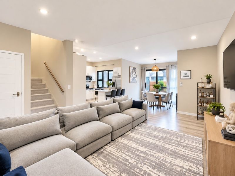 Spacious open-plan living, dining, and kitchen area featuring modern finishes, recessed lighting, and a functional layout with an adjoining staircase.