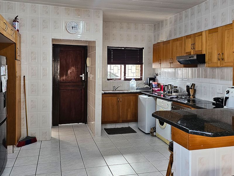 A functional kitchen featuring wooden cabinetry, granite countertops, tiled backsplash, and tiled flooring, offering a practical layout with integrated appliances.