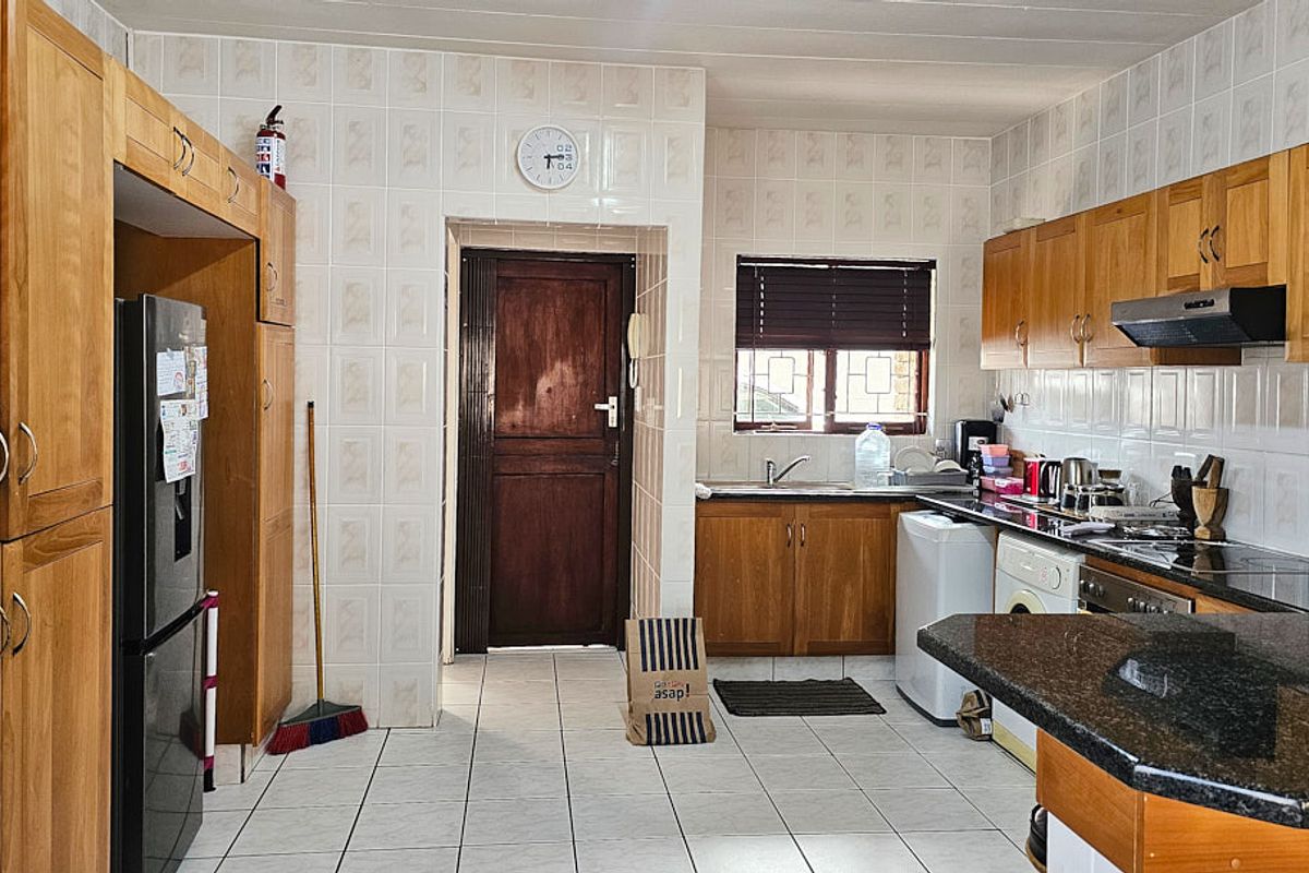 A functional kitchen featuring wooden cabinetry, granite countertops, tiled backsplash, and integrated appliances, offering a classic layout with ample storage space.