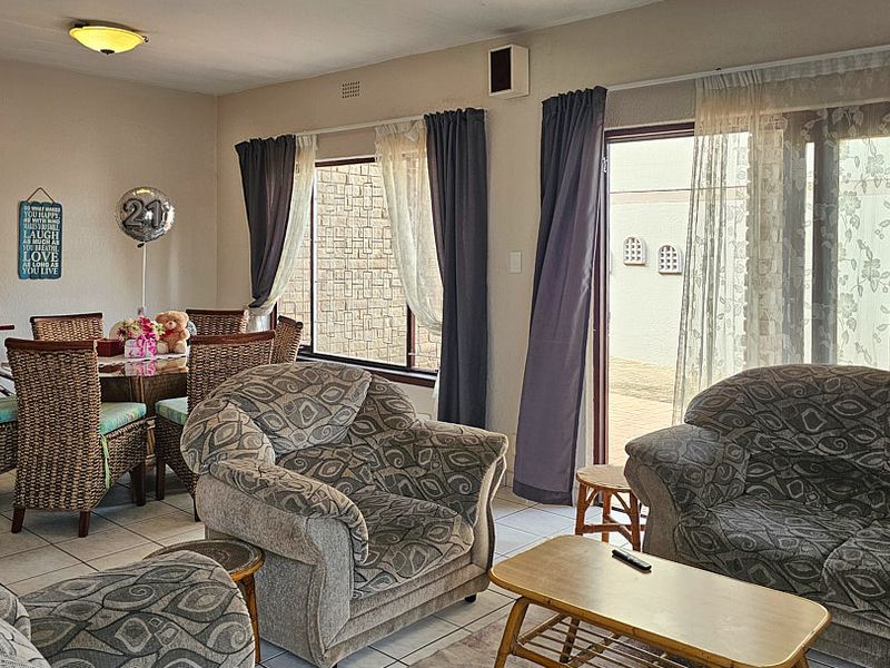 Open plan living and dining area featuring tiled flooring, large windows, and a sliding glass door providing access to the exterior.